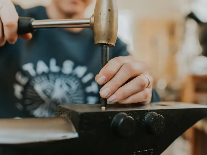 Hammering a silver rivet flat on an anvil