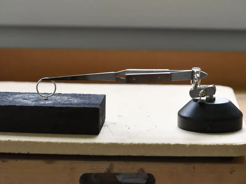 Third-hand tweezers and a solder block set up on the bench